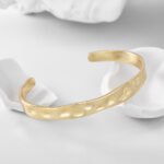 Wholesale Irregular Cuff Bracelet featuring convex-concave hammered texture on a 14K gold-plated copper band from junejewelry.com—factory price, free shipping.