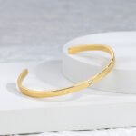 Wholesale single CZ cuff bracelet featuring a minimalist design and 14K gold plated copper from junejewelry.com