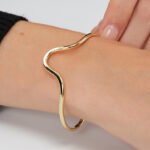 Wholesale wave cuff bracelet featuring a minimalist wavy design and 14K gold plated copper from junejewelry.com