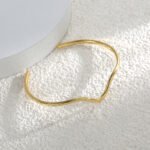 Wholesale wave cuff bracelet featuring a minimalist wavy design and 14K gold plated copper from junejewelry.com