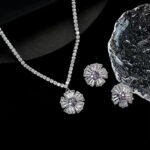 Radiant sunburst cubic zirconia necklace and earring set with platinum plating on a black background.