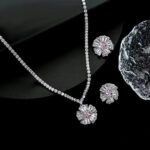 Radiant sunburst cubic zirconia necklace and earring set with platinum plating on a black background.