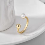 Geometric Ball Pearl Ring featuring an open copper band plated in 18K gold with a spherical bead and a freshwater pearl on opposing ends from junejewelry.com—factory price, free shipping.