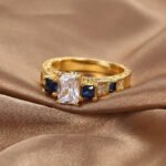 Wholesale square zircon ring featuring an 18k gold plated copper design with a prominent square-cut zircon and intricate micro-pave white zircons from junejewelry.com