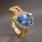 Wholesale French modern minimalist teardrop blue zircon ring for women, 18K gold plated copper with a sparkling blue zircon from junejewelry.com
