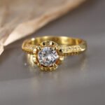 Wholesale French four prong zircon ring, 18K gold plated copper, with a sparkling zircon, ideal for fashion jewelry wholesale from junejewelry.com.