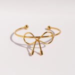 Wholesale bow knot bracelet with polished 8-shape twist design in 18K gold plated brass – sweet cool fashion cuff from JuneJewelry.com.