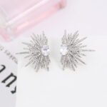Wholesale starburst stud earrings with a central oval cubic zirconia and micro-pavé stones, platinum-plated brass and 925 silver needle from JuneJewelry.com.