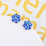 Wholesale Colorful Flower Stud Earrings with a gold plated finish and emerald-colored and clear cubic zirconia stones from JuneJewelry.com – unique fashion jewelry for bulk orders.