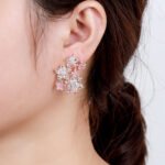 Wholesale Colorful Flower Stud Earrings with a gold plated finish and ruby-colored and clear cubic zirconia stones from JuneJewelry.com – unique fashion jewelry for bulk orders.