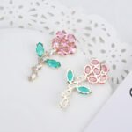 Wholesale Flower Dangle Earrings with a gold plated finish and green and clear cubic zirconia stones from JuneJewelry.com – unique fashion jewelry for bulk orders.