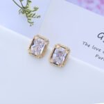 Wholesale vintage gold earrings with an emerald cut CZ stone and a detailed ornate frame from junejewelry.com – classic fashion jewelry for bulk orders.