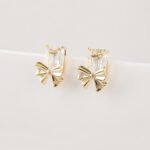 Wholesale starburst stud earrings with a central oval CZ and pavé stones on a platinum-plated brass base from junejewelry.com – unique fashion jewelry for bulk orders.