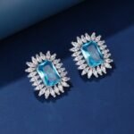 Wholesale blue gemstone earrings with a zircon sunburst on rhodium plated copper and 925 sterling silver pins from JuneJewelry.com – elegant fashion jewelry for bulk orders.