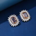 Wholesale blue gemstone earrings with a zircon sunburst on rhodium plated copper and 925 sterling silver pins from JuneJewelry.com – elegant fashion jewelry for bulk orders.