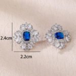 Wholesale ruby red gemstone earrings with a clear zircon cluster on rhodium plated copper and 925 sterling silver pins from JuneJewelry.com – elegant fashion jewelry for bulk orders.