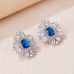 Wholesale ruby red gemstone earrings with a clear zircon cluster on rhodium plated copper and 925 sterling silver pins from JuneJewelry.com – elegant fashion jewelry for bulk orders.