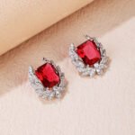 Wholesale zircon leaf earrings with a central red stone and a leaf motif with white cubic zirconia, platinum plated on a copper base with a 925 silver needle, from JuneJewelry.com.