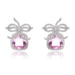 Wholesale zircon bow earrings with a cushion-cut pink center stone and cubic zirconia accents, platinum plated with a 925 silver needle, from JuneJewelry.com.