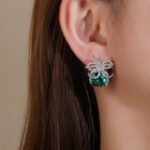 Wholesale zircon bow earrings with a cushion-cut pink center stone and cubic zirconia accents, platinum plated with a 925 silver needle, from JuneJewelry.com.