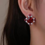 Wholesale ruby red gemstone stud earrings with a zircon cluster on rhodium plated copper and 925 sterling silver pins from JuneJewelry.com – elegant fashion jewelry for bulk orders.