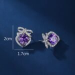 Wholesale pink zircon bow earrings with a central pink stone and cubic zirconia accents, platinum plated on a copper base with a 925 silver needle, from JuneJewelry.com.