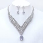 Wholesale platinum plated necklace set with cubic zirconia stones. Elegant brass V-shaped necklace and matching drop earrings for formal wear.