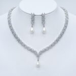 Wholesale platinum plated set with pearl and zirconia. Brass V-shaped necklace and matching leaf-design earrings for bridal wear.