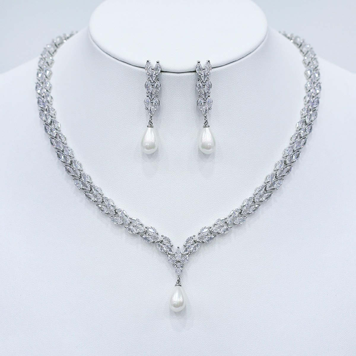 CN10814.451.A Wholesale platinum plated set with pearl and zirconia. Brass V-shaped necklace and matching leaf-design earrings for bridal wear.
