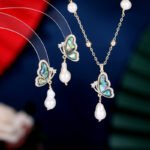 Abalone Shell Butterfly Pearl Jewelry Set in gold plating. The necklace and drop earrings feature a butterfly pendant with rainbow abalone shell wings and a dangling baroque freshwater pearl.