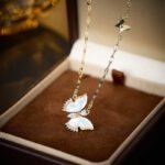 Wholesale Butterfly Shell Jewelry Set shown in gold and silver colors. The elegant set includes a butterfly pendant necklace, stud earrings, and an adjustable ring, all featuring iridescent Mother of Pearl wings and micro-paved Cubic Zirconia accents.