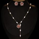 Wholesale Baroque Pearl Camellia Set displayed on a black bust. Features a Y-style necklace with small baroque pearls and a black micro-pave Camellia pendant, matching the Camellia stud earrings.