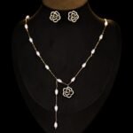 Wholesale Baroque Pearl Camellia Set displayed on a black bust. Features a Y-style necklace with small baroque pearls and a black micro-pave Camellia pendant, matching the Camellia stud earrings.