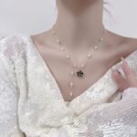 Wholesale Baroque Pearl Camellia Set displayed on a black bust. Features a Y-style necklace with small baroque pearls and a black micro-pave Camellia pendant, matching the Camellia stud earrings.