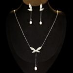 Wholesale Butterfly Tassel Pearl CZ Set in a platinum-plated finish on a black display bust. Features a matching necklace and drop earrings, both in a delicate butterfly shape with paved wings, ending in an elegant pearl tassel/drop.