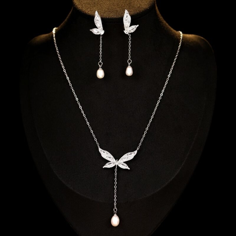 Wholesale Butterfly Tassel Pearl CZ Set in a platinum-plated finish on a black display bust. Features a matching necklace and drop earrings, both in a delicate butterfly shape with paved wings, ending in an elegant pearl tassel/drop.