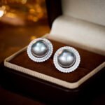 Wholesale Halo Pearl CZ Jewelry Set displayed in a box, showing a ring, stud earrings, and a pendant necklace. The design features a large round imitation pearl encircled by a halo of glittering cubic zirconia. Available in Golden Pearl/Yellow Gold and Black Pearl/Platinum finishes.