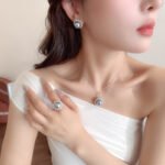 Wholesale Halo Pearl CZ Jewelry Set displayed in a box, showing a ring, stud earrings, and a pendant necklace. The design features a large round imitation pearl encircled by a halo of glittering cubic zirconia. Available in Golden Pearl/Yellow Gold and Black Pearl/Platinum finishes.