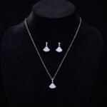 Wholesale Fan Shape Shell Set with natural Mother of Pearl fan motif and delicate CZ connector stones. The set includes a matching necklace and stud earrings, shown in both gold and platinum finishes on a black display.