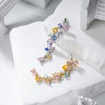 Wholesale Colorful Zircon Flower Tassel Jewelry Set in Dopamine style, featuring multi-colored inlaid zircon gemstones, a flower tassel necklace (choker/collar chain), and matching earrings, available in 18K Gold Plated or White Gold Plated copper from junejewelry.com.