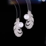 Wholesale Feather Pearl Zircon Set in a platinum-plated finish on a black display bust. Features a matching necklace and stud earrings, both in a curved feather shape paved with cubic zirconia, centered with a single white pearl.