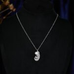 Wholesale Feather Pearl Zircon Set in a platinum-plated finish on a black display bust. Features a matching necklace and stud earrings, both in a curved feather shape paved with cubic zirconia, centered with a single white pearl.