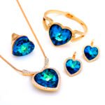 Wholesale 4-Piece Swarovski Element Heart Jewelry Set in silver plating, showing necklace, bangle, ring, and earrings with blue crystals.