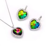 Swarovski Element heart crystal jewelry set showing three color options: iridescent green, purple-aqua AB, and deep aqua blue, with a matching necklace and leverback earrings.