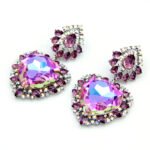 Swarovski Element heart crystal dangle earrings, featuring a suspended pear-shaped crystal in Vitrail Light (iridescent purple/green) and Bermuda Blue (deep electric blue) color effects.