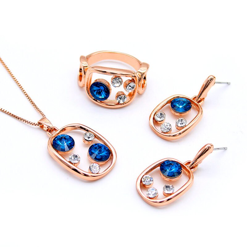 Wholesale blue crystal geometric jewelry set in rose gold plating with an open rectangular pendant, ring, and dangle earrings featuring blue and clear round crystals from JuneJewelry.com – unique and high-quality.