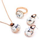 Wholesale crystal round jewelry set in rose gold plating with a large faceted white crystal ring, pendant, and drop earrings with black enamel detail from JuneJewelry.com – unique and high-quality.