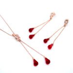 Wholesale red crystal tassel jewelry set in rose gold plating with a knot pendant and long dangle earrings with red crystal teardrops from JuneJewelry.com – unique and high-quality.