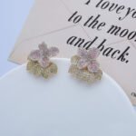 Wholesale flower zircon earrings with white pavé crystals on real gold plated copper from JuneJewelry.com – luxury floral studs for bulk orders.