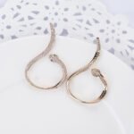 Wholesale serpent hoop earrings with white zircon pavé and green eyes on silver plated copper from JuneJewelry.com – trendy jewelry for bulk orders.